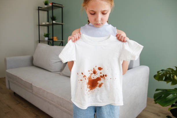 The child spilled coffee on his clothes. The concept of a stain on a t-shirt.